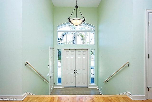 entryway with wood finished floors and a towering ceiling