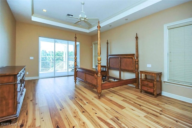 bedroom featuring visible vents, access to exterior, baseboards, light wood-style floors, and a tray ceiling