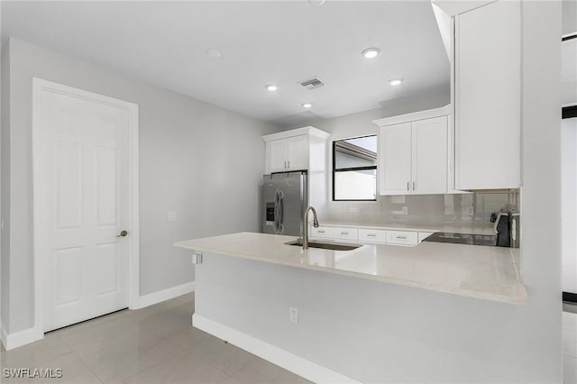 kitchen featuring decorative backsplash, sink, range, stainless steel fridge with ice dispenser, and kitchen peninsula