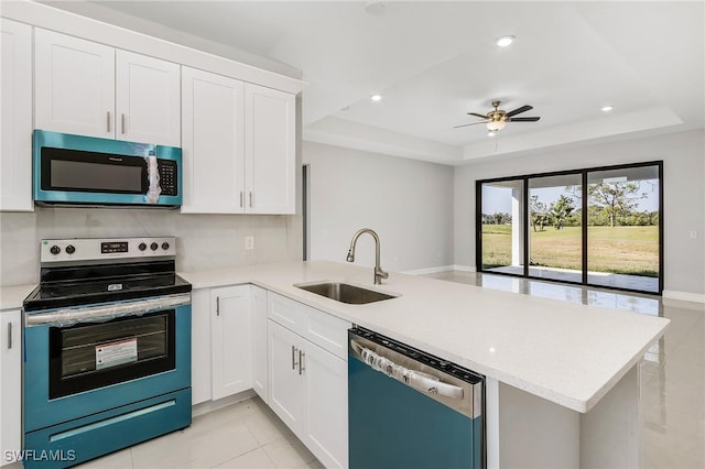 kitchen with ceiling fan, a raised ceiling, sink, kitchen peninsula, and stainless steel appliances