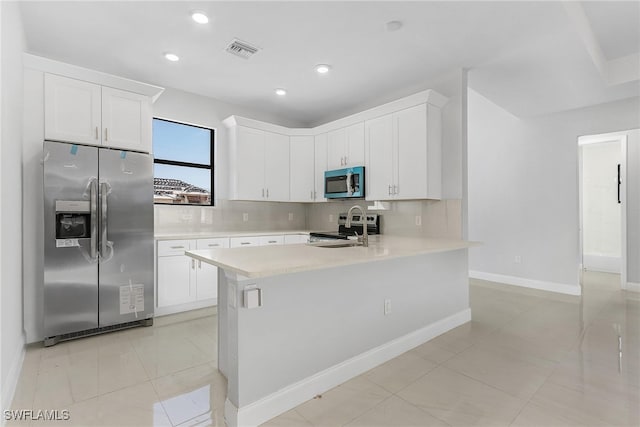 kitchen featuring stainless steel appliances, decorative backsplash, white cabinets, light tile patterned floors, and kitchen peninsula