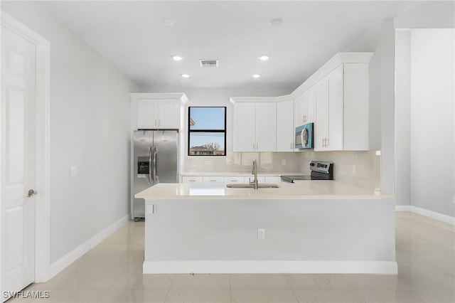 kitchen with decorative backsplash, kitchen peninsula, light tile patterned floors, and stainless steel appliances