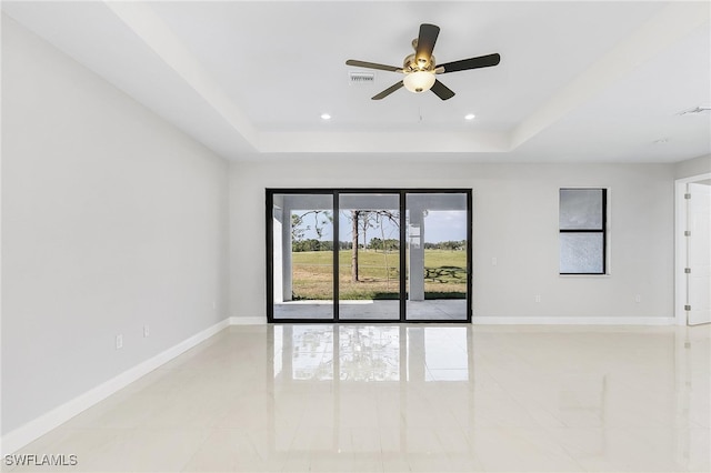 unfurnished room featuring ceiling fan, a raised ceiling, and light tile patterned floors