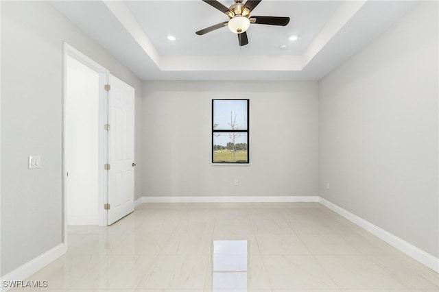 interior space with ceiling fan, a raised ceiling, and light tile patterned flooring