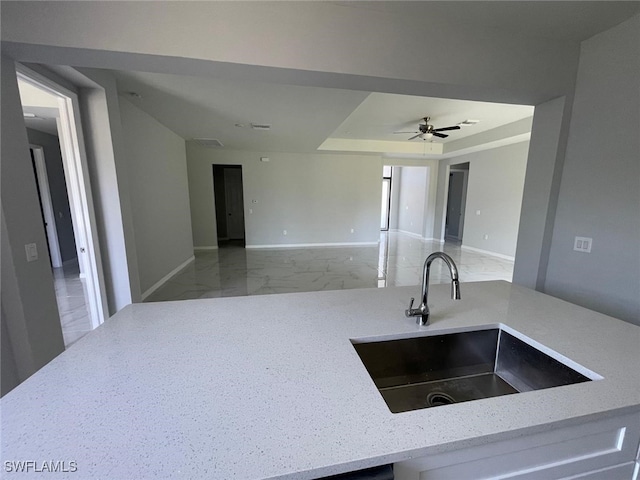 kitchen featuring light stone countertops, sink, and ceiling fan