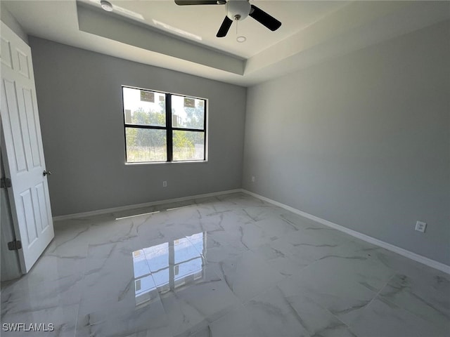 unfurnished room with ceiling fan and a raised ceiling