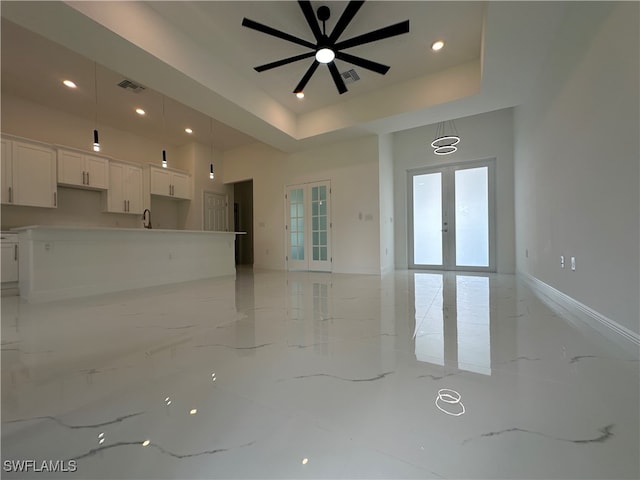 unfurnished living room with french doors, sink, a raised ceiling, and ceiling fan