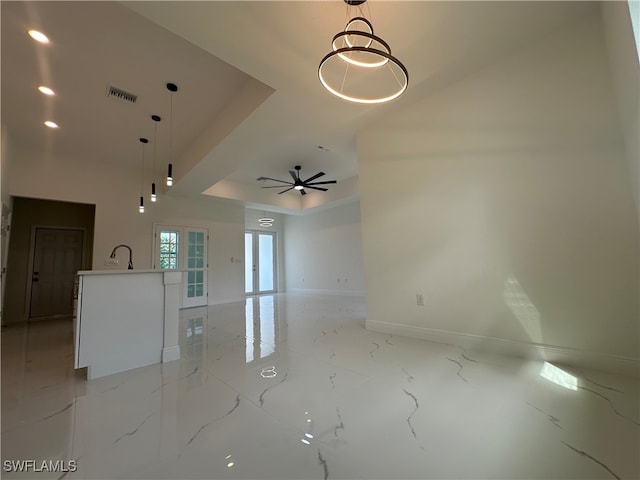 unfurnished living room featuring sink, ceiling fan, and a tray ceiling