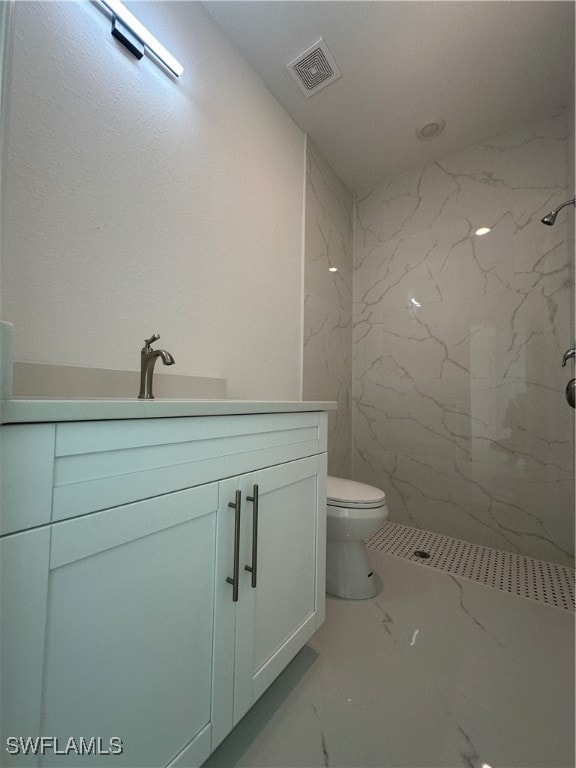 bathroom with vanity, toilet, and tiled shower