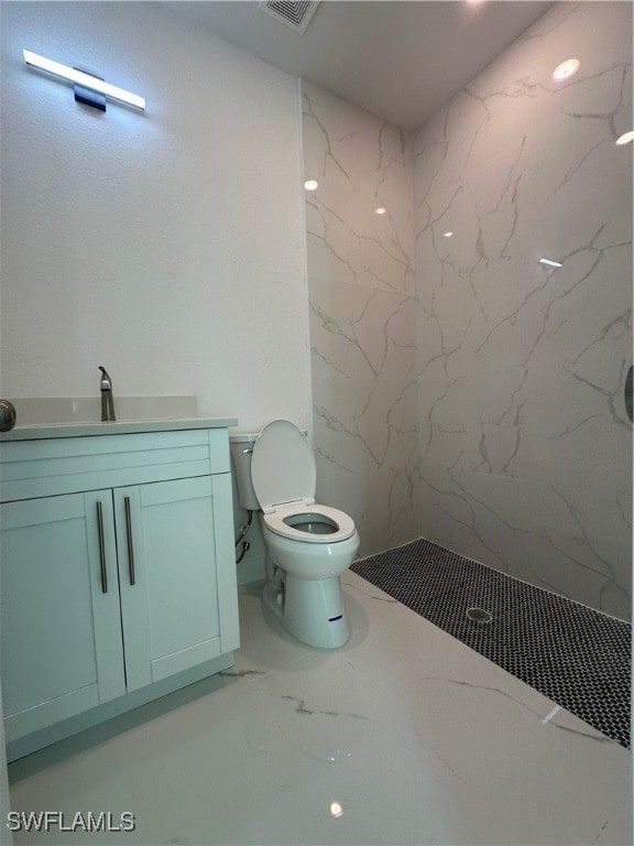 bathroom featuring vanity, a tile shower, and toilet