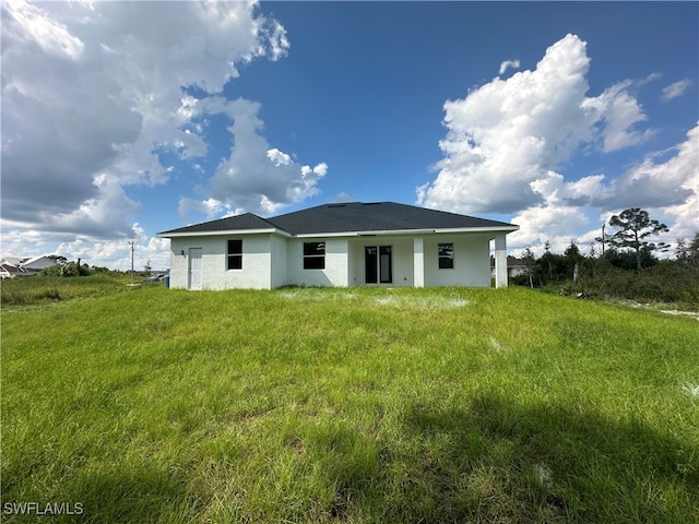 rear view of property featuring a lawn