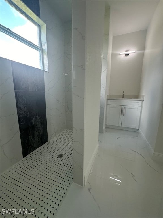 bathroom with a tile shower and vanity