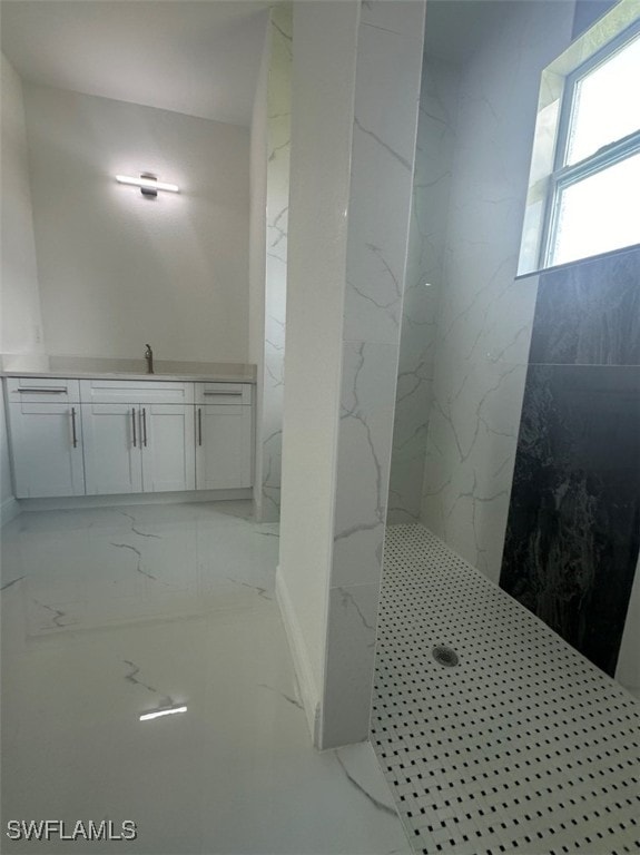 bathroom with a tile shower and vanity