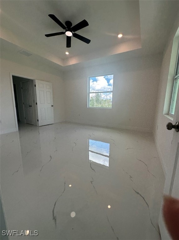 unfurnished room with a raised ceiling and ceiling fan