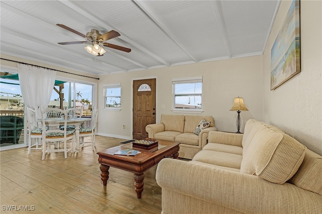 living area with ceiling fan, beam ceiling, light wood-style flooring, and baseboards