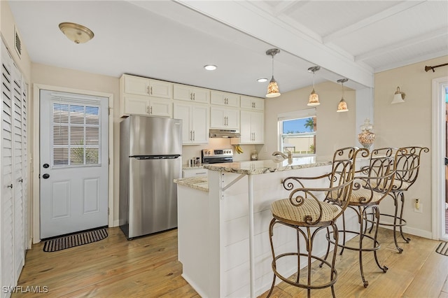 kitchen with light stone counters, decorative light fixtures, stainless steel appliances, beamed ceiling, and a kitchen breakfast bar