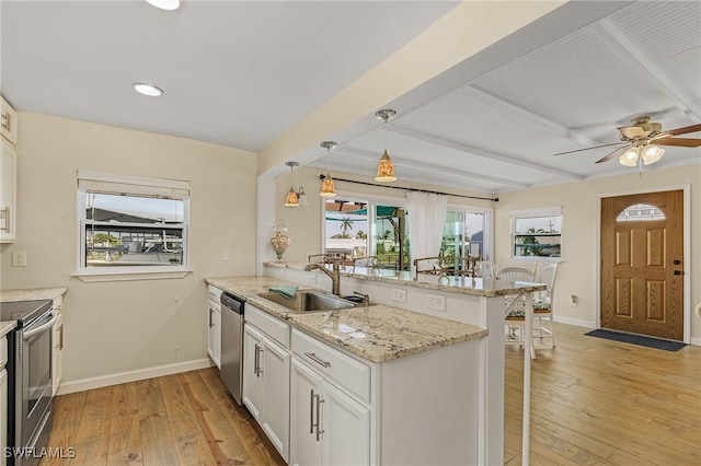 kitchen with a breakfast bar area, a peninsula, stainless steel appliances, a sink, and white cabinets