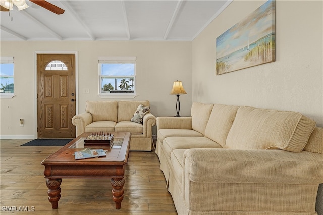 living area with beamed ceiling, wood finished floors, and baseboards