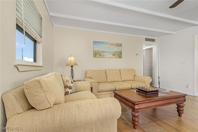 living area featuring visible vents, wood finished floors, and beamed ceiling