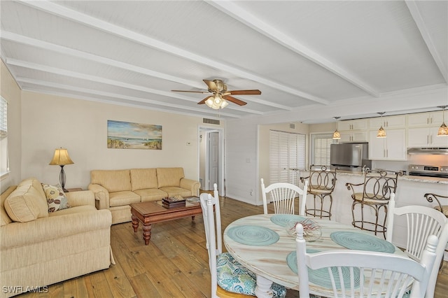 dining space featuring visible vents, baseboards, a ceiling fan, beam ceiling, and light wood finished floors