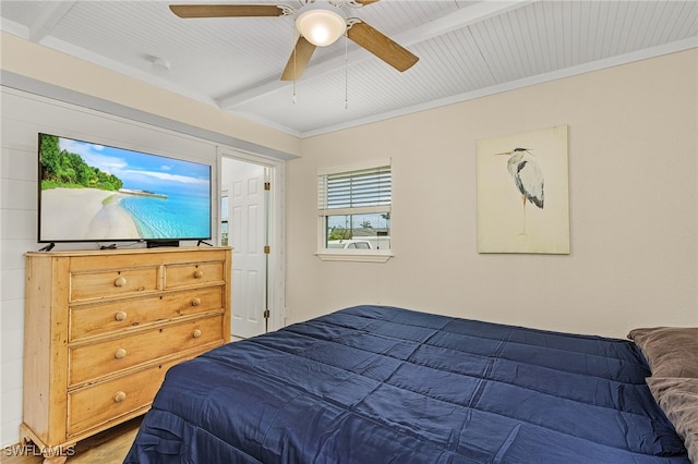 bedroom with a ceiling fan, ornamental molding, beam ceiling, and wood finished floors