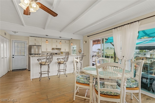 dining room featuring ceiling fan, light wood finished floors, beamed ceiling, and visible vents