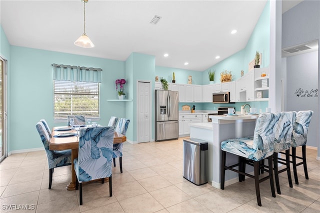 kitchen featuring hanging light fixtures, light tile patterned floors, stainless steel appliances, kitchen peninsula, and white cabinets