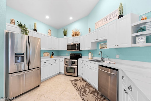 kitchen with sink, appliances with stainless steel finishes, light stone counters, light tile patterned floors, and white cabinets