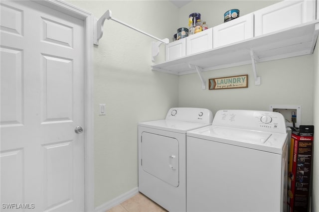 clothes washing area with cabinets, light tile patterned flooring, and washer and clothes dryer