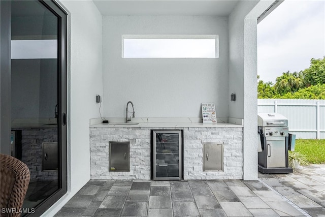 view of patio / terrace with beverage cooler, a sink, fence, and area for grilling