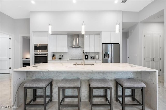 kitchen with tasteful backsplash, modern cabinets, stainless steel appliances, wall chimney range hood, and white cabinetry