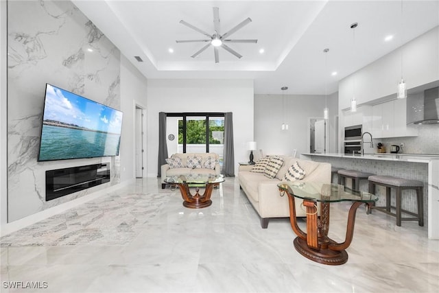 living area featuring a high ceiling, a tray ceiling, a ceiling fan, and recessed lighting