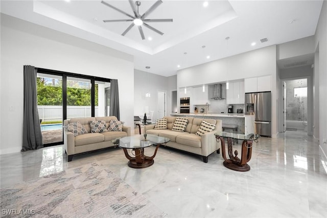 living area featuring marble finish floor, a tray ceiling, and a towering ceiling