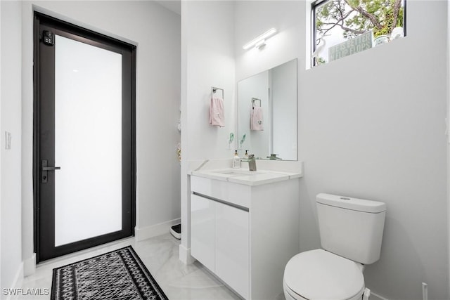 bathroom featuring toilet, baseboards, and vanity