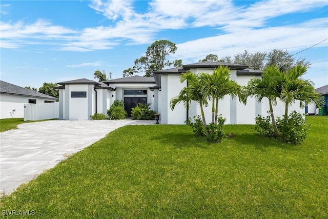 view of front facade with a front lawn, decorative driveway, an attached garage, and stucco siding