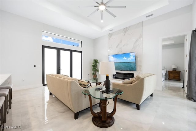 living area featuring french doors, a tray ceiling, visible vents, and baseboards