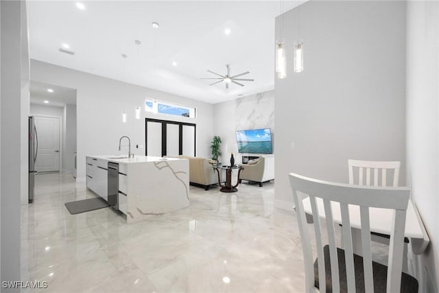 interior space featuring marble finish floor, appliances with stainless steel finishes, a sink, an island with sink, and modern cabinets