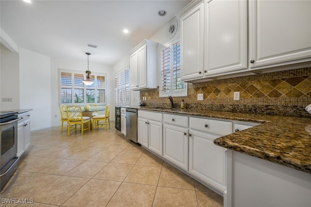 kitchen with dark stone counters, stove, decorative backsplash, and white cabinets