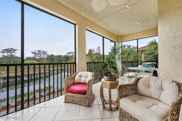 sunroom featuring ceiling fan and a water view