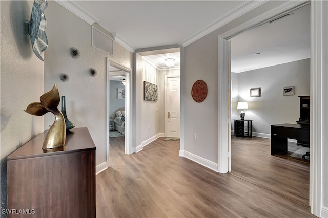 hallway with baseboards, visible vents, crown molding, and wood finished floors