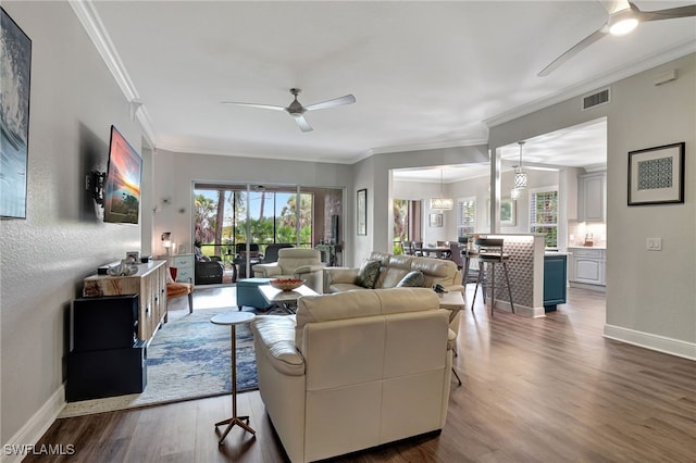 living room featuring visible vents, ornamental molding, ceiling fan, wood finished floors, and baseboards