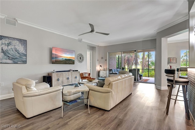 living room featuring ornamental molding, visible vents, baseboards, and wood finished floors