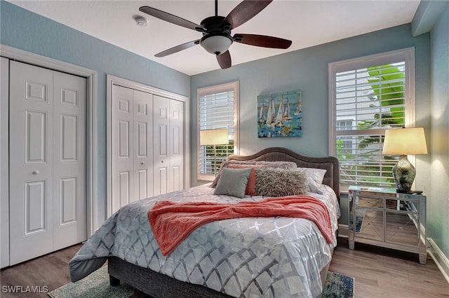 bedroom with multiple closets, a ceiling fan, baseboards, and wood finished floors