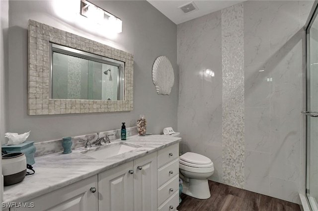 full bath with visible vents, toilet, wood finished floors, walk in shower, and vanity