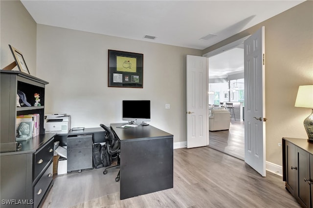 office area featuring light wood finished floors, visible vents, and baseboards