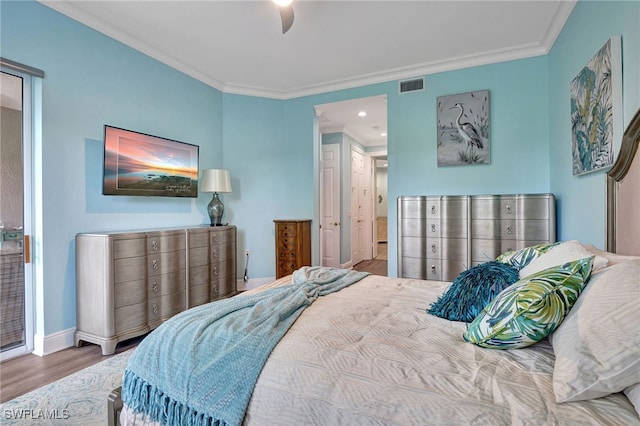 bedroom with visible vents, crown molding, baseboards, and wood finished floors