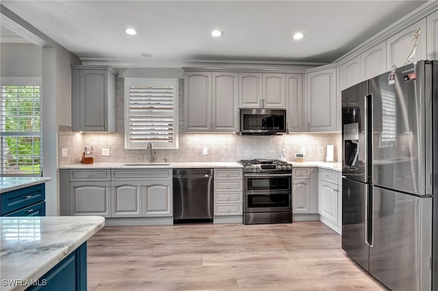 kitchen with appliances with stainless steel finishes, gray cabinetry, and sink