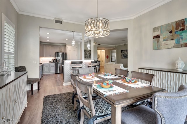 dining area with recessed lighting, ceiling fan with notable chandelier, wood finished floors, visible vents, and crown molding