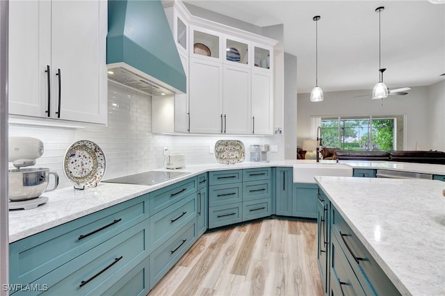 kitchen with backsplash, premium range hood, white cabinetry, black electric stovetop, and light wood-type flooring