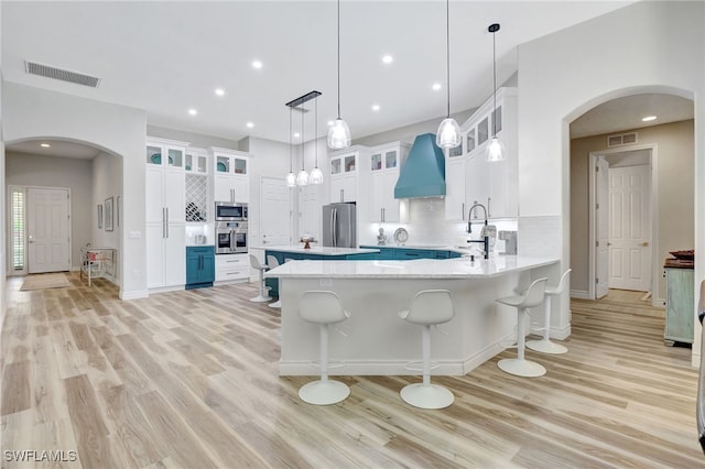 kitchen featuring appliances with stainless steel finishes, decorative light fixtures, white cabinets, and light hardwood / wood-style floors